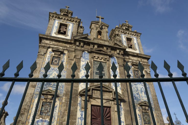 Santo Ildefonso church with arrow fence. . Blue relegious tiles. Cloudy sky. Porto, Portugal